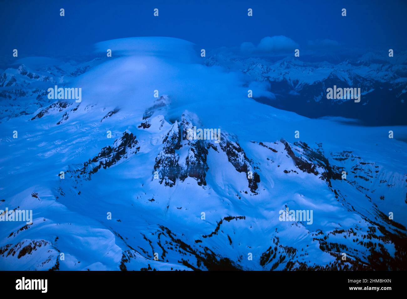 Mountain Aerials, mount Baker with Lenticular cloud over summit with blue cast Stock Photo