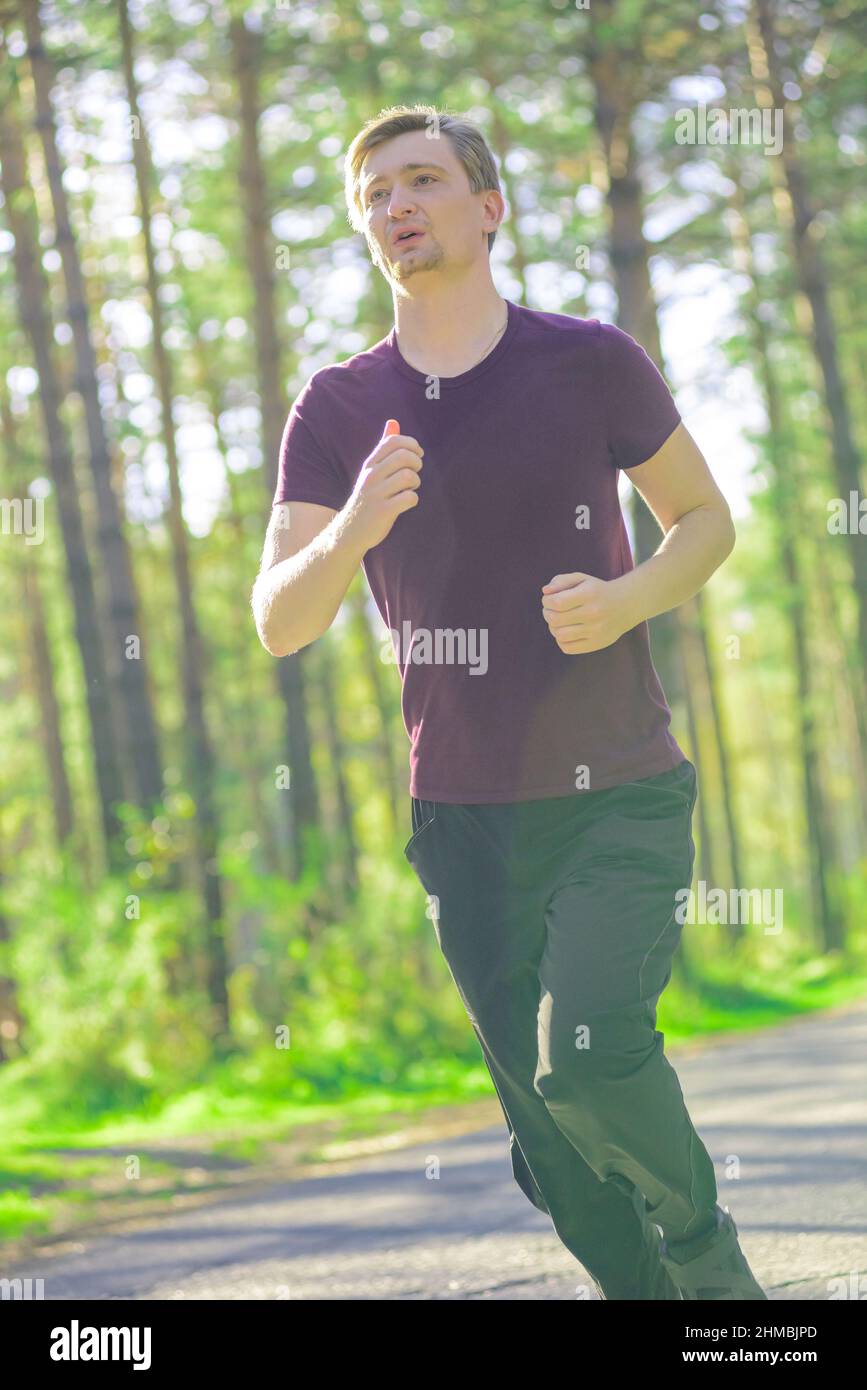 Running man jogging in city park at beautiful summer day. Sport fitness