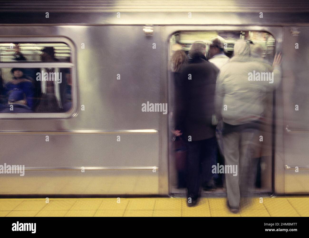 Subway car overcrowding departure. New York City Transit Authority public transportation at rush hour. Open subway train door people pushing to enter. Stock Photo