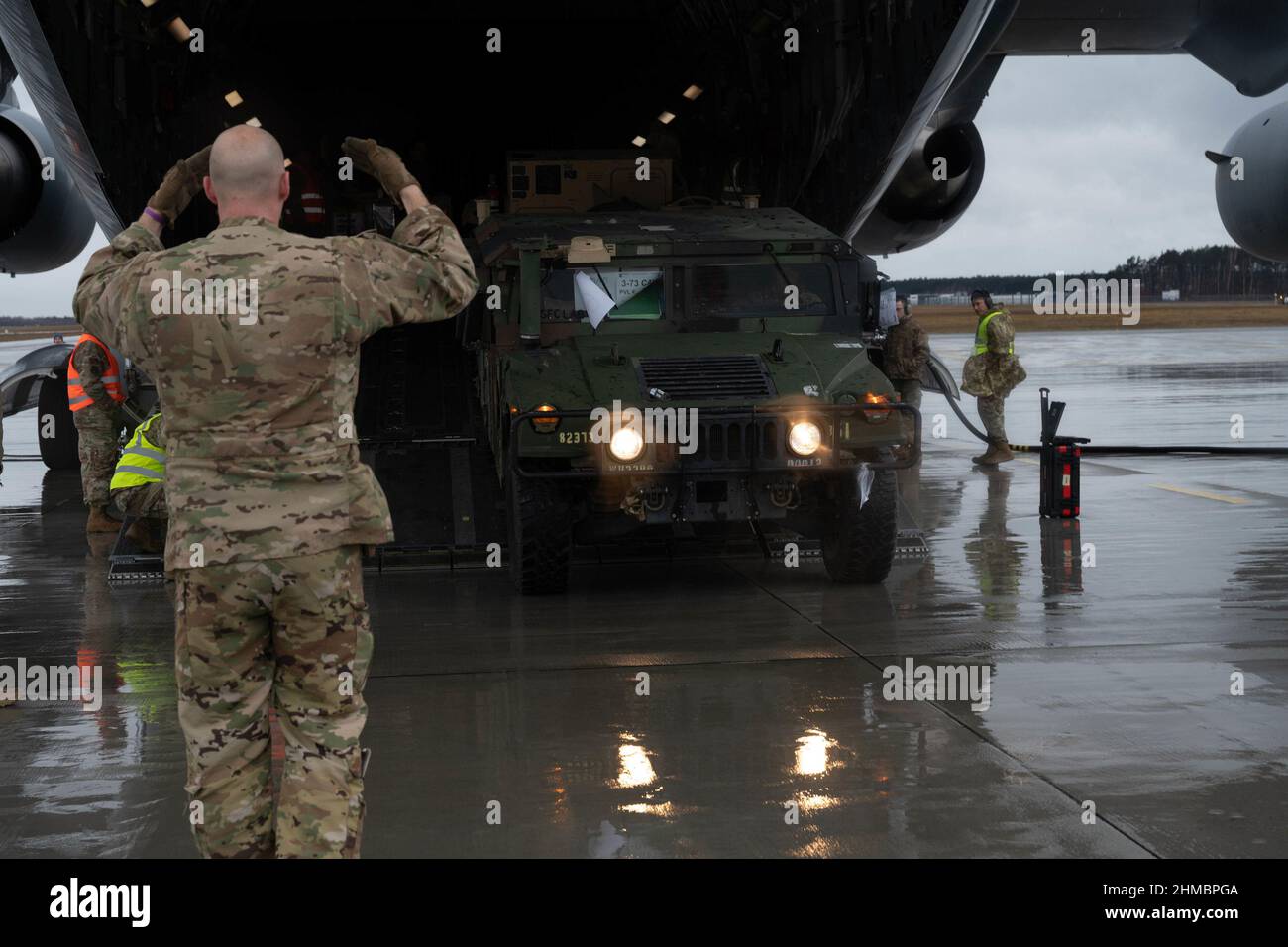 Jasionka, Poland. 08th Feb, 2022. A U.S. Air Force Airman marshals a U.S. Army Humvee out of a C-17 Globemaster III aircraft assigned to the 62nd Airlift Wing from Joint Base Lewis-McChord, Washington, in Rzeszów-Jasionka Airport, Poland, on February 7, 2022. U.S. personnel and equipment arrived to support NATO Allies and partners in order to improve a collective readiness, interoperability, and relationships. Photo by Senior Airman Taylor Slater/U.S. Air Force/UPI Credit: UPI/Alamy Live News Stock Photo