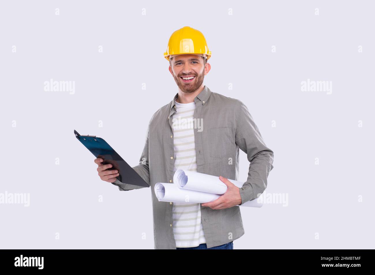 Construction Worker Holding House Plan and Clipboard in Hands. Architect Holding Blueprints. Yellow Hard Helmet. Worker Smilling Stock Photo