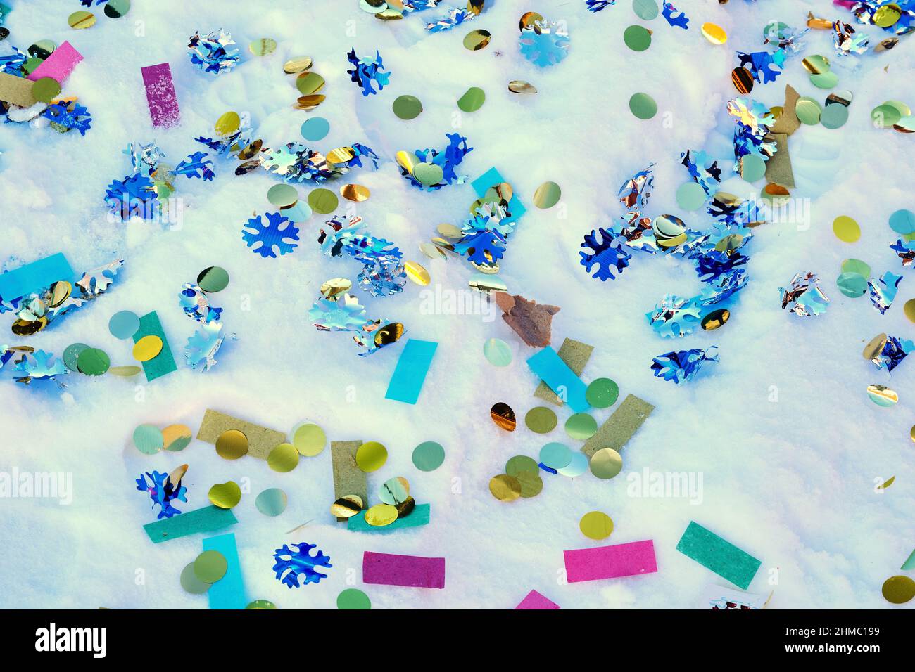 Festive confetti from a cracker is scattered on fresh snow. Holidays and events backgrounds Stock Photo