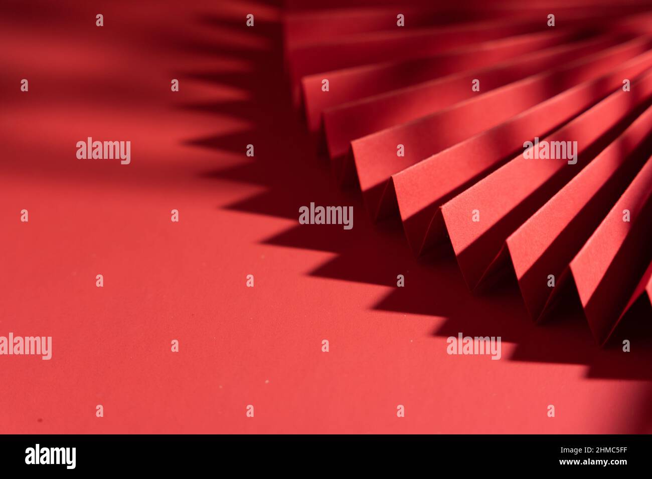 Chinese style paper folding fan with shadow isolated on red background ...