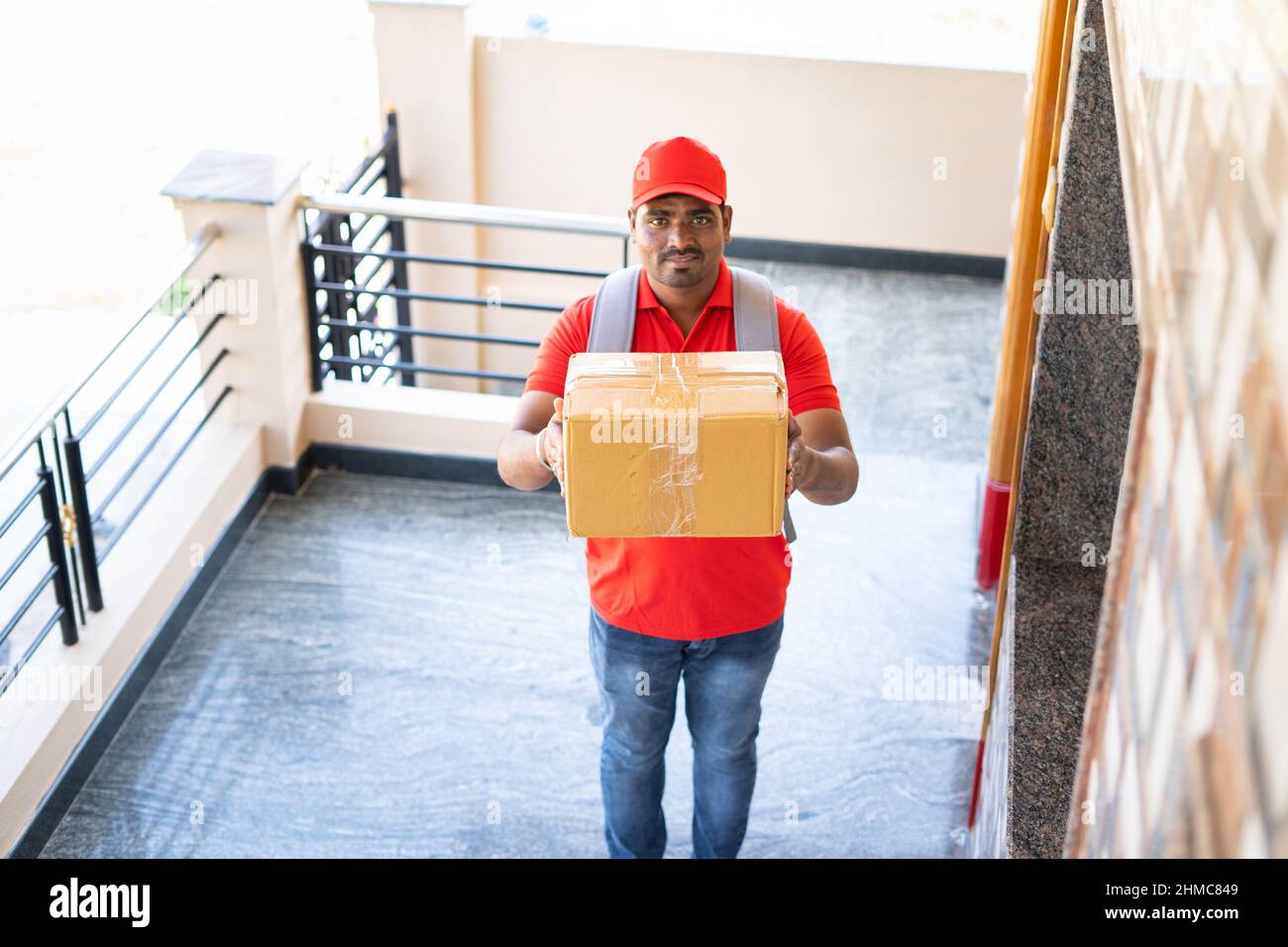 focus on box, Delivery boy placing parcel in front of door after showing parcel to cctv or security camera - concept of security, safety and home Stock Photo