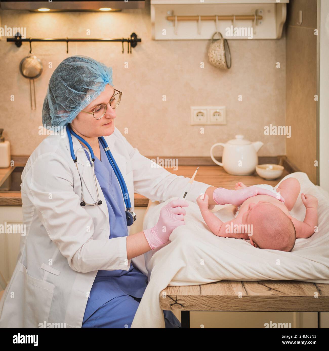 Doctor checks the temperature of the newborn baby with a thermometer. A