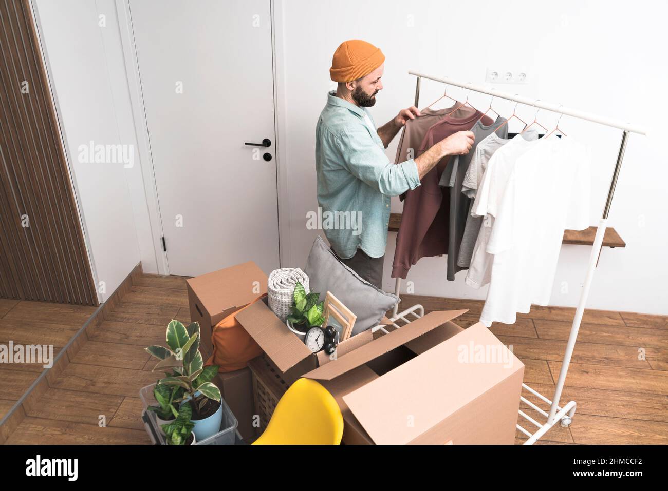 Adult men hanging clothes on a clothes rack in new home on moving day