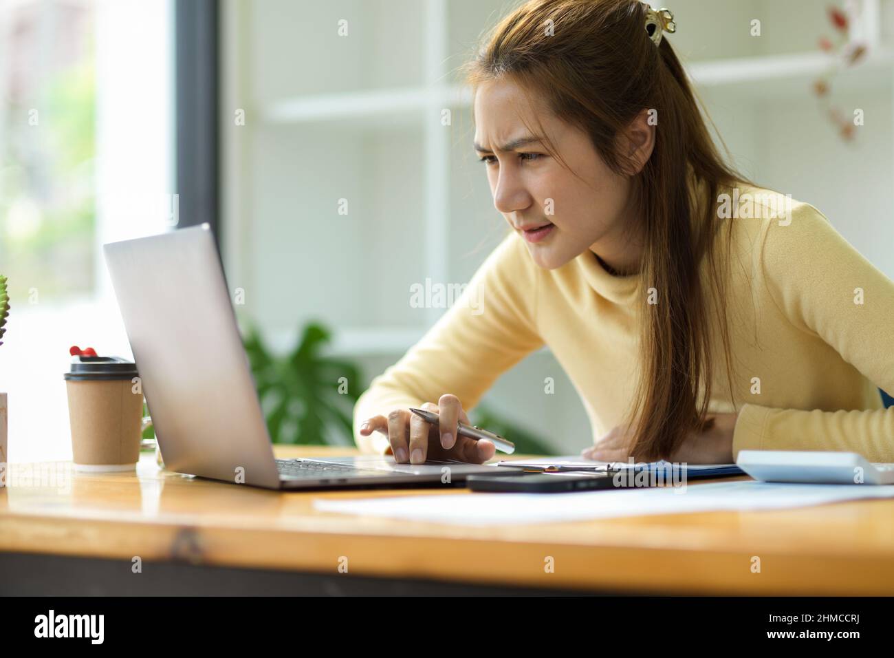 Confused asian young businesswoman annoyed by online problem, project rejected. Stressed female student looking at broken pc. Stock Photo