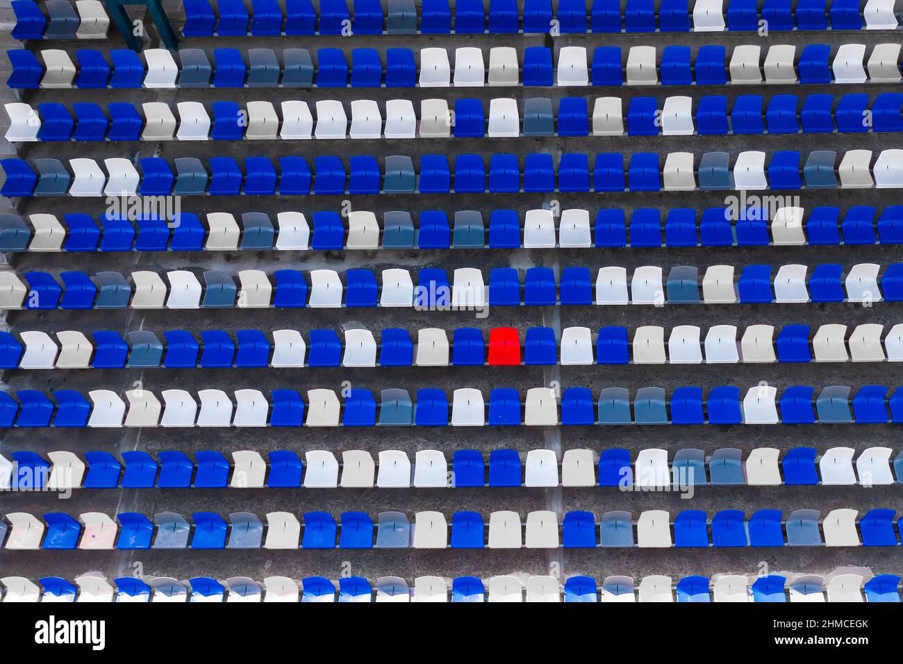 seats at the stadium view from above. A red chair among the blue ones Stock Photo