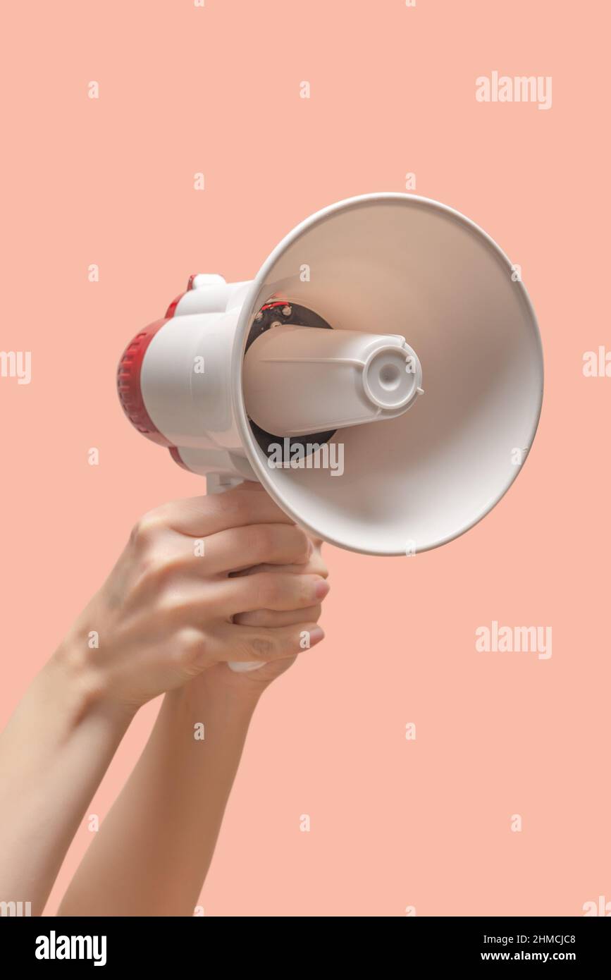 Megaphone in woman hands on a pink background. Copy space. Stock Photo