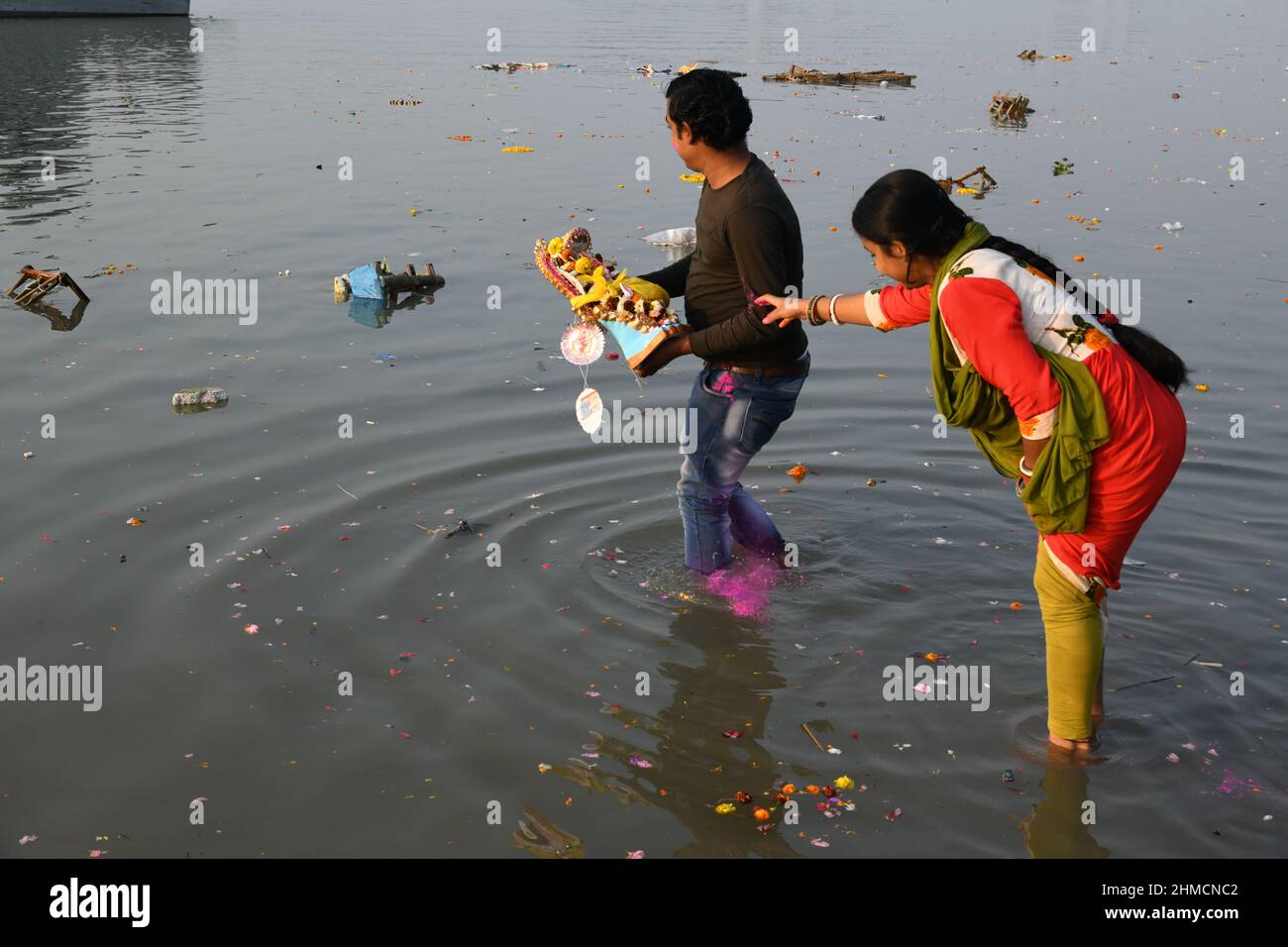 A family floating Hindu goddess Saraswati idol for immersion on the