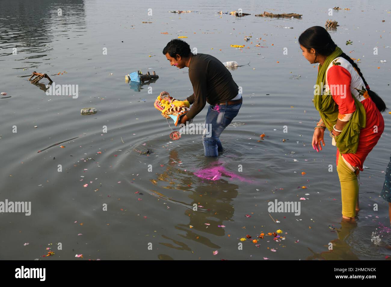 A family floating Hindu goddess Saraswati idol for immersion on the