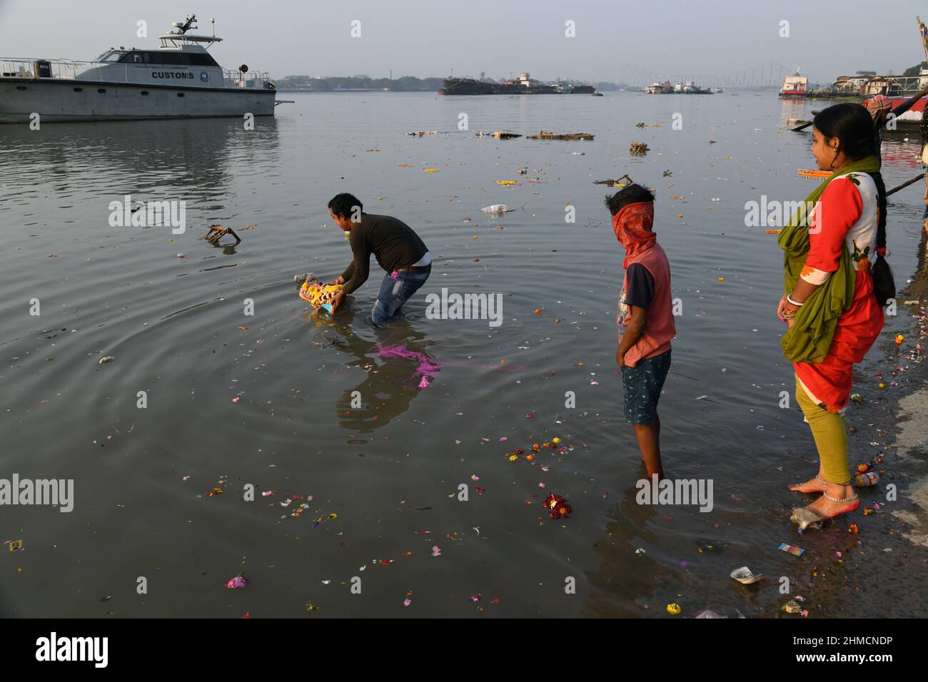 A family floating Hindu goddess Saraswati idol for immersion on the