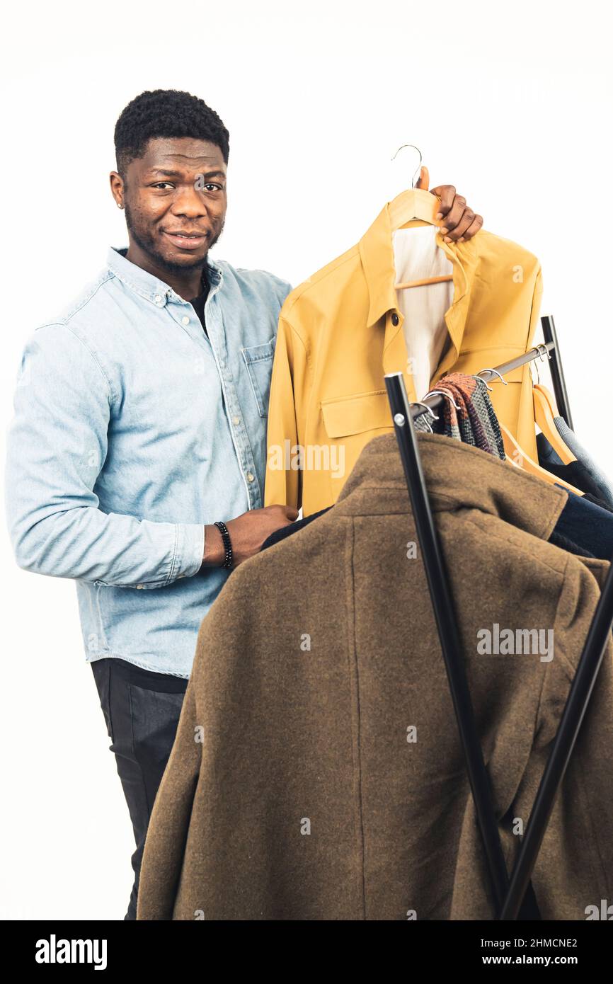 black man smiling showing yellow jacket clothe rack white background - portrait shot. High quality photo Stock Photo