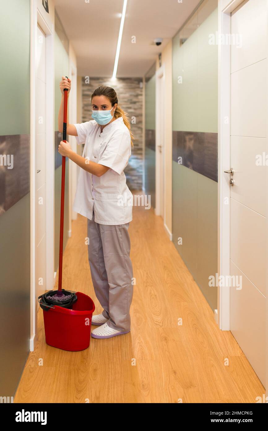 Woman standing holding mop in a bucket looking at camera in hallway of  physiotherapy centre Stock Photo - Alamy