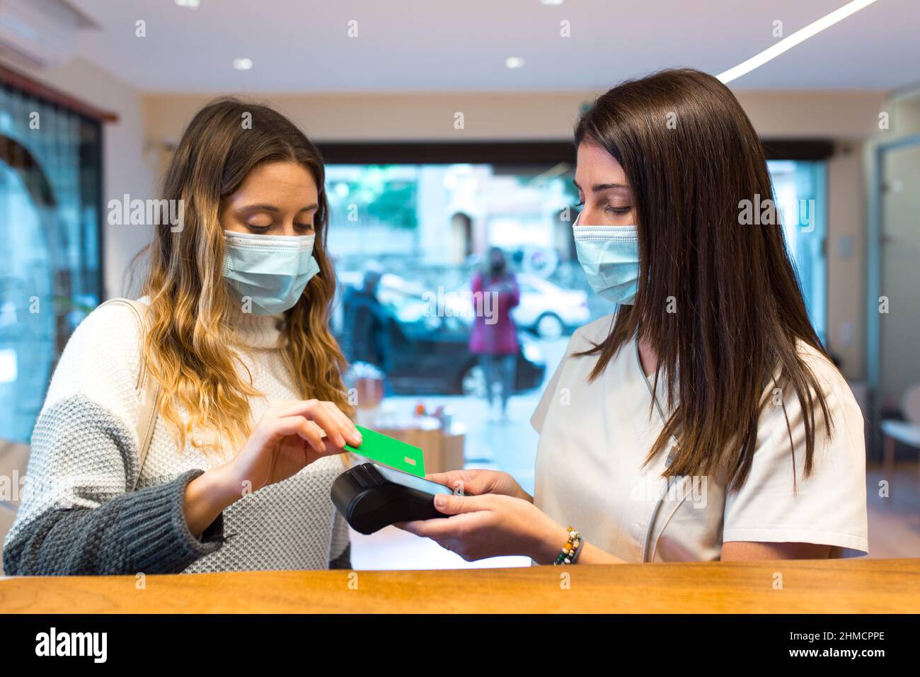 Female patient paying with a credit card for health treatment at the clinic reception. Stock Photo