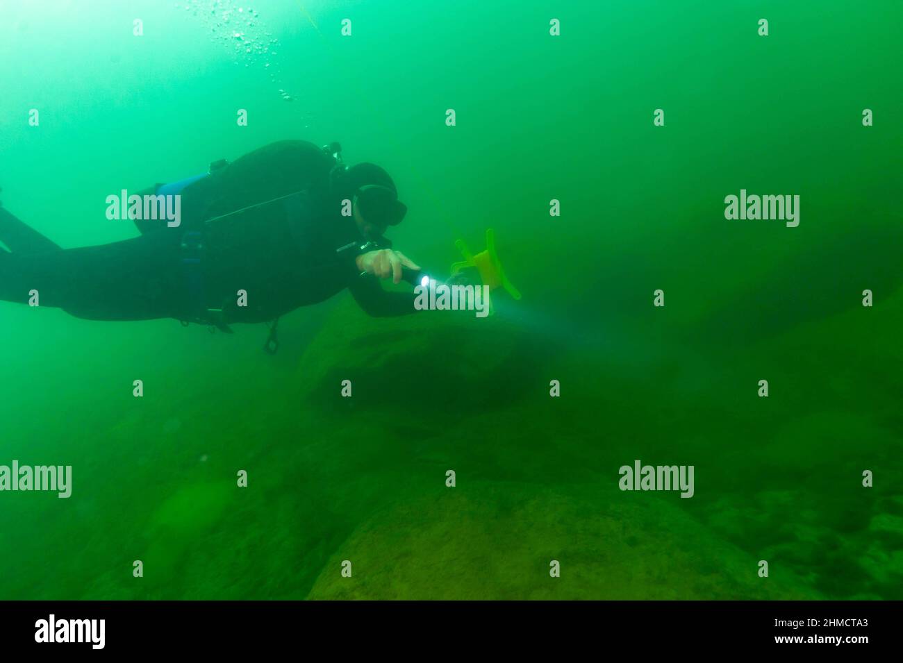 SCUBA diver exploring a cloudy inland lake and boulders with a diving