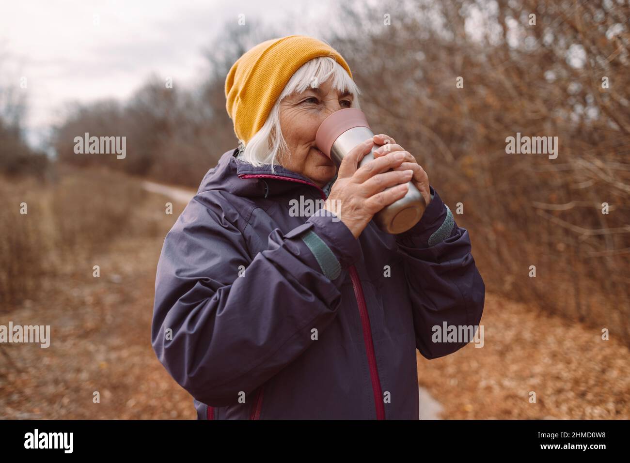 Elderly woman traveler holding thermos mug in the city traveller in beautiful nature. Zero waste eco concept Stock Photo