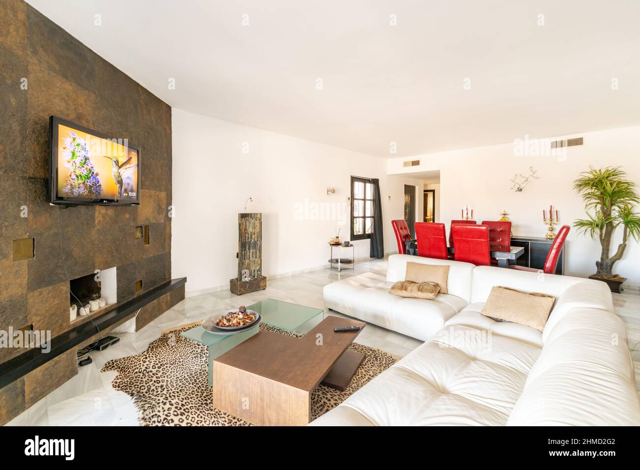 a open plan living room including a cosy fire place and large white sofa Stock Photo