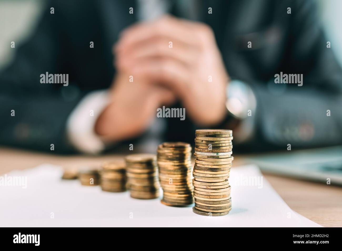 Retirement saving plant concept, businessman with coin stack on office desk, selective focus Stock Photo