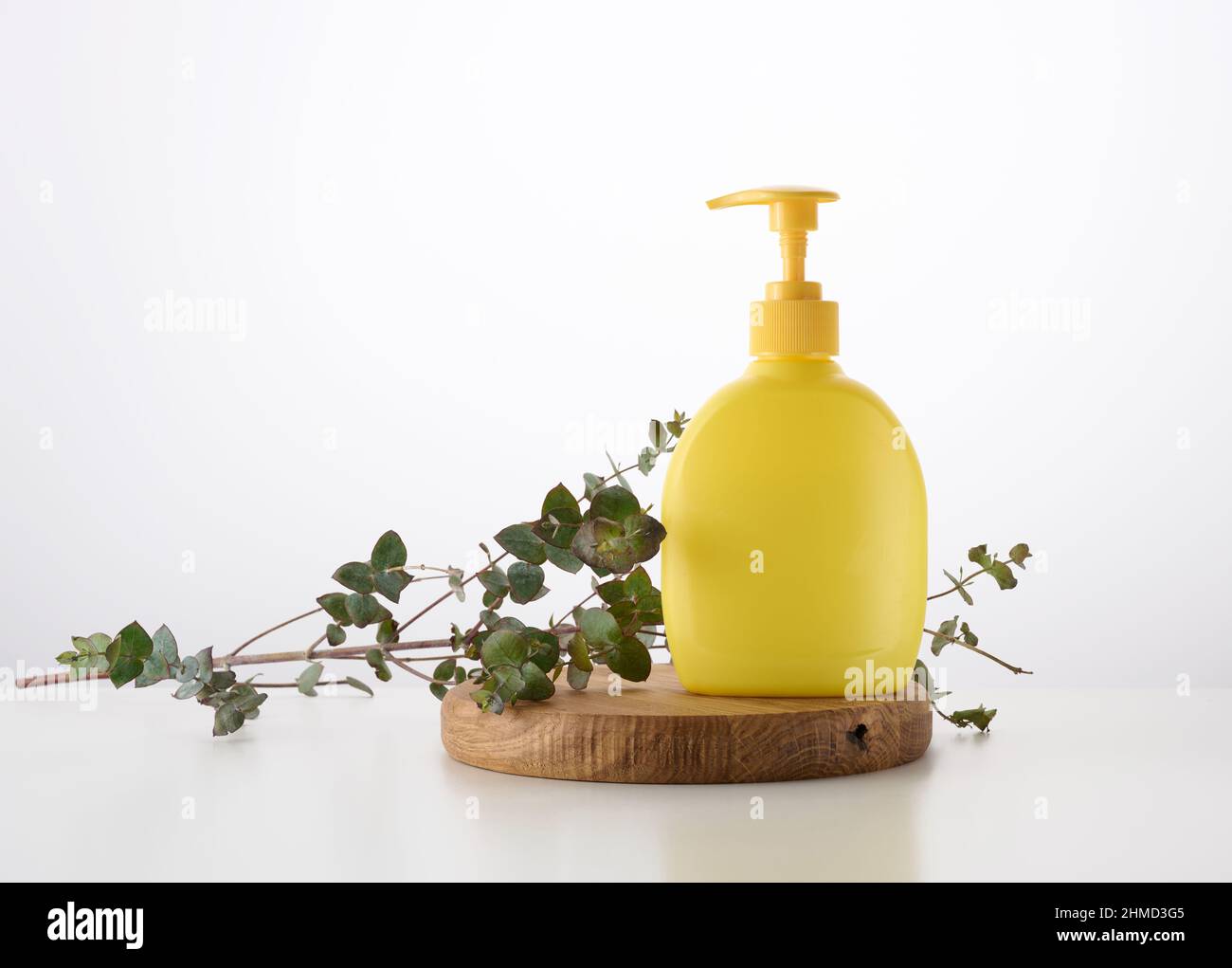 https://c8.alamy.com/comp/2HMD3G5/yellow-plastic-container-with-a-dispenser-on-a-wooden-background-and-a-branch-of-eucalyptus-on-a-white-background-container-for-liquid-soap-shampoo-2HMD3G5.jpg