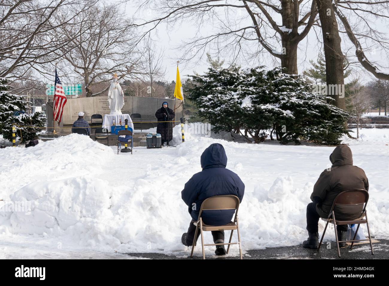 BAYSIDERS. Devout Christians attend a winter afternoon mass in a park in Queens New York at the site of the 1964 Worlds Fair Vatican Pavilion. Stock Photo