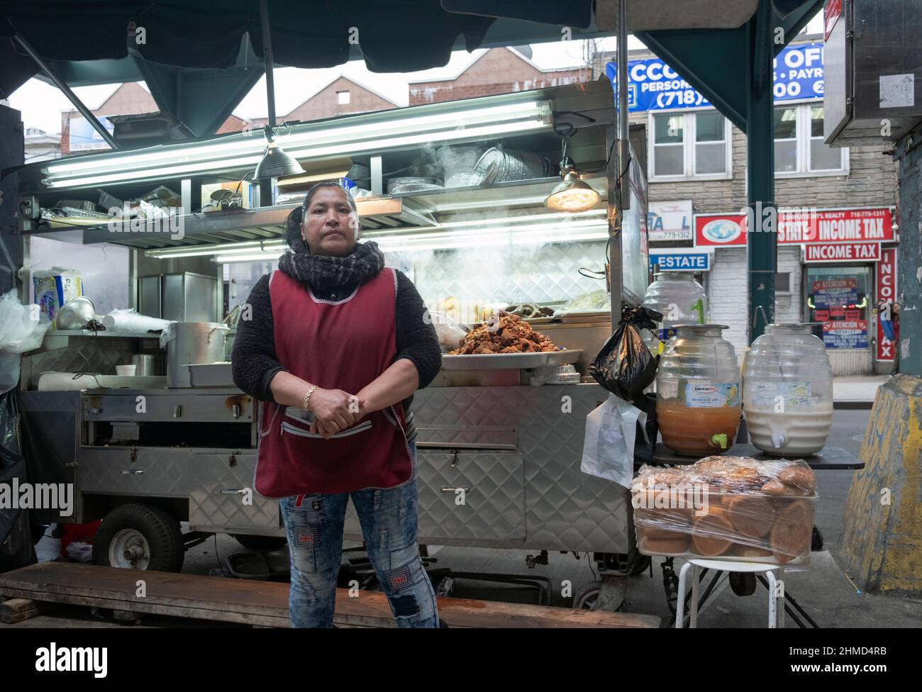 A South American woman selling grilled meats & other foods from a cart just off Roosevelt Ave. and under the elevated subway trains . Stock Photo