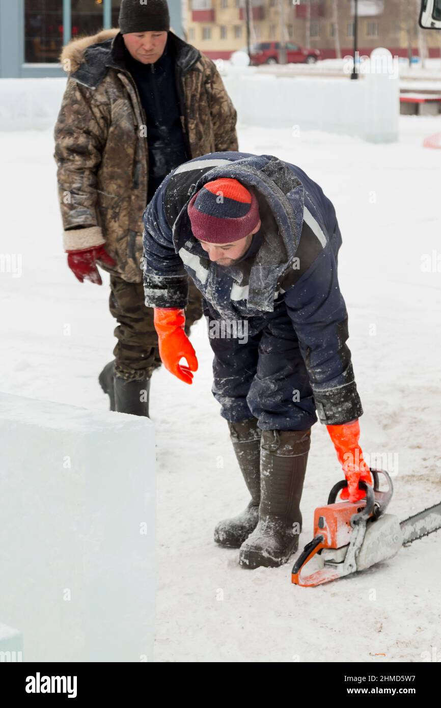 Worker with a chainsaw in hand at the assembly site Stock Photo