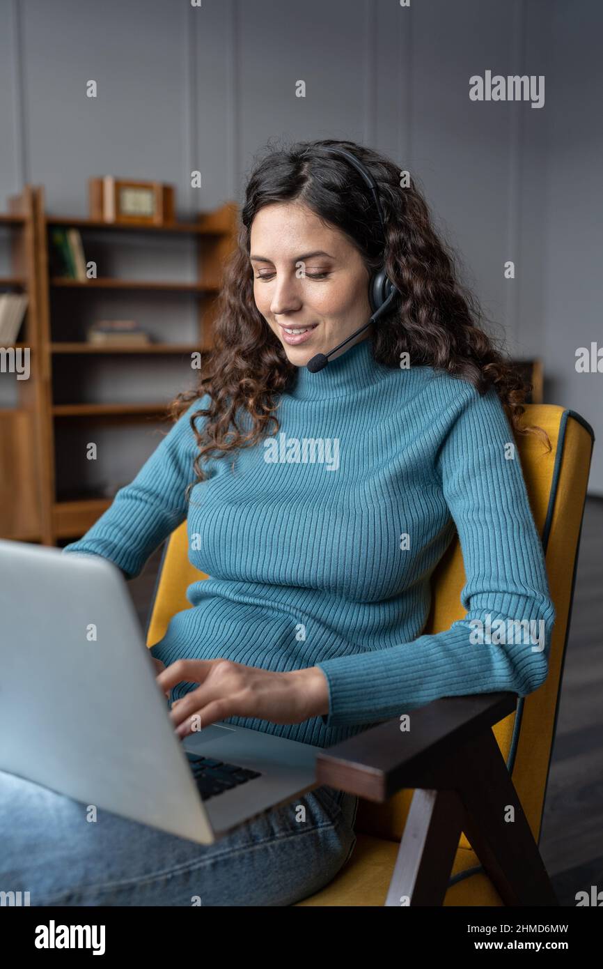 Young female freelancer using headset for remote work, communicating with colleagues via videocall Stock Photo