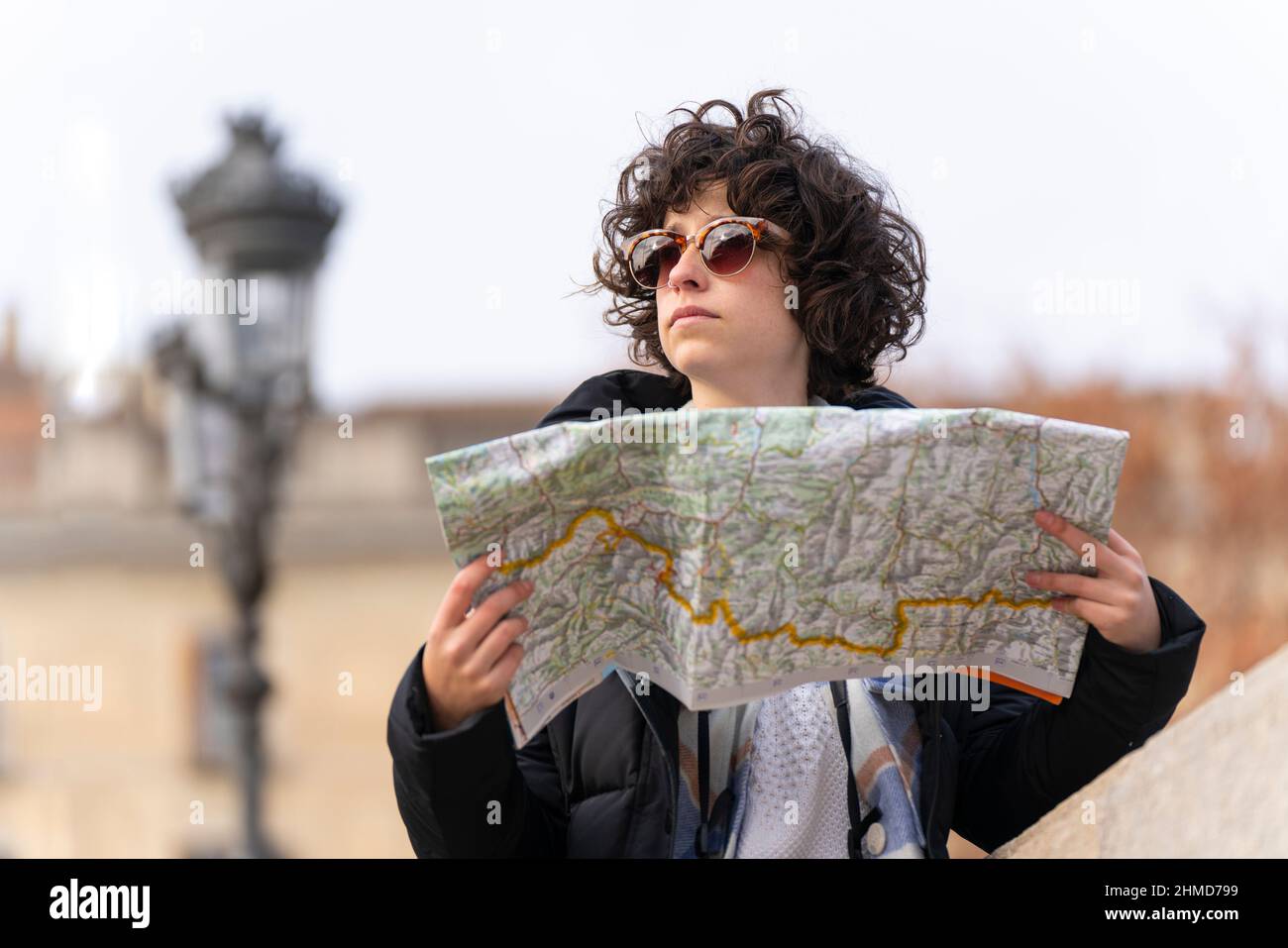 Young tourist woman searches for a place in the city with the help of a map Stock Photo