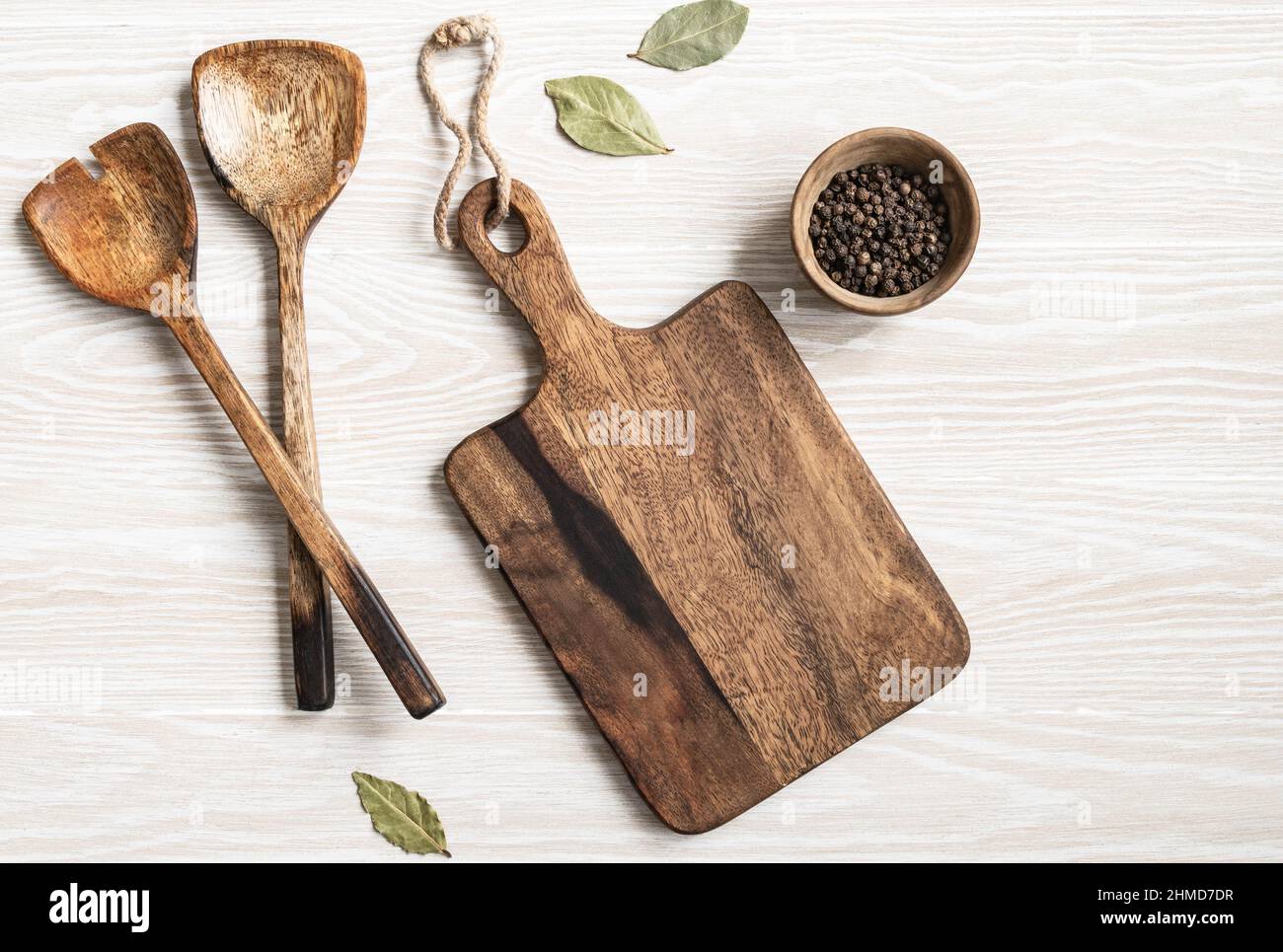Minimal wood white kitchen background with brown cutting board, various spices, appliances and cotton napkin. Kitchen utensils on texture white table. Stock Photo