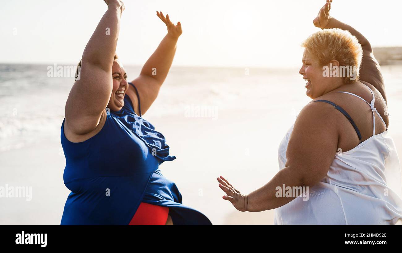 Curvy women dancing on the beach having fun during summer vacation - Focus on right face Stock Photo