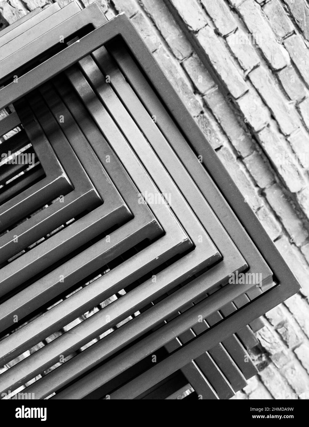 Geometric abstraction from several metal straight rods against the background of a brick wall. Black and white photo Stock Photo