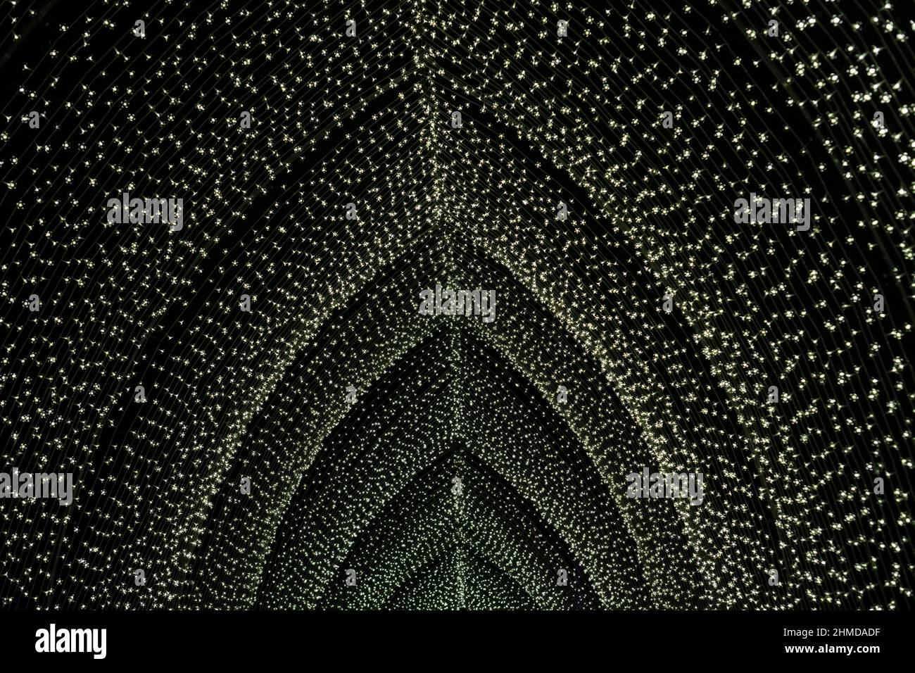 yellow outdoor light tunnel made of many little light bulbs at night