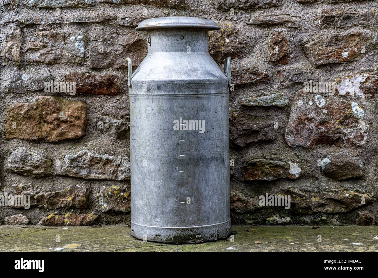 Milk Urn up against a stone wall Stock Photo