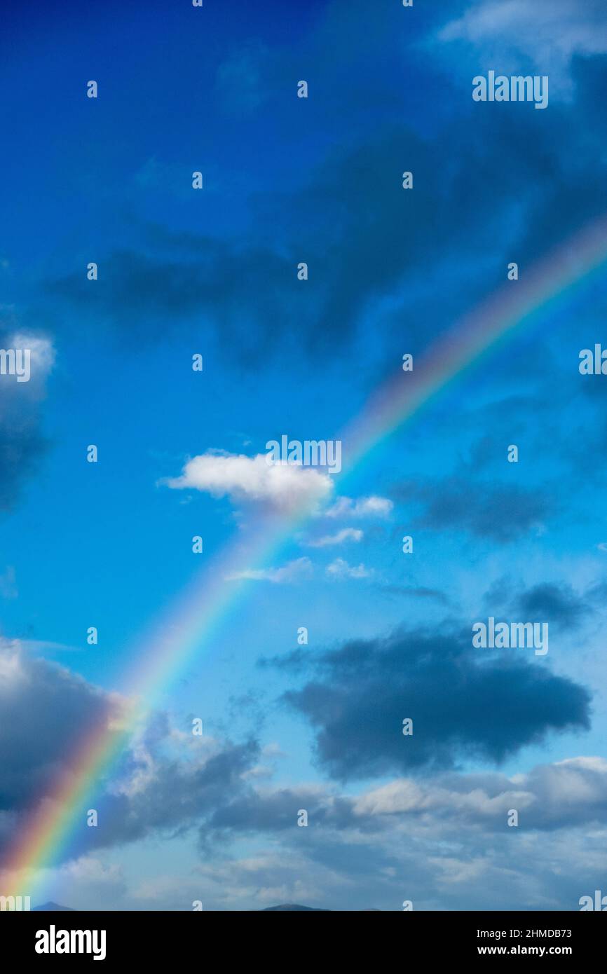 Colorful rainbow with cloud against blue sky Stock Photo - Alamy