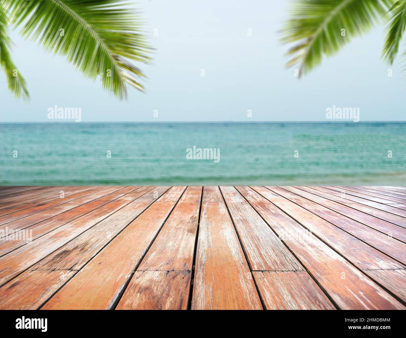 Empty wood table with blur ocean outdoor background bokeh seascape and coconut leaf ,Mockup for display or montage of seafood or sun protect product b Stock Photo