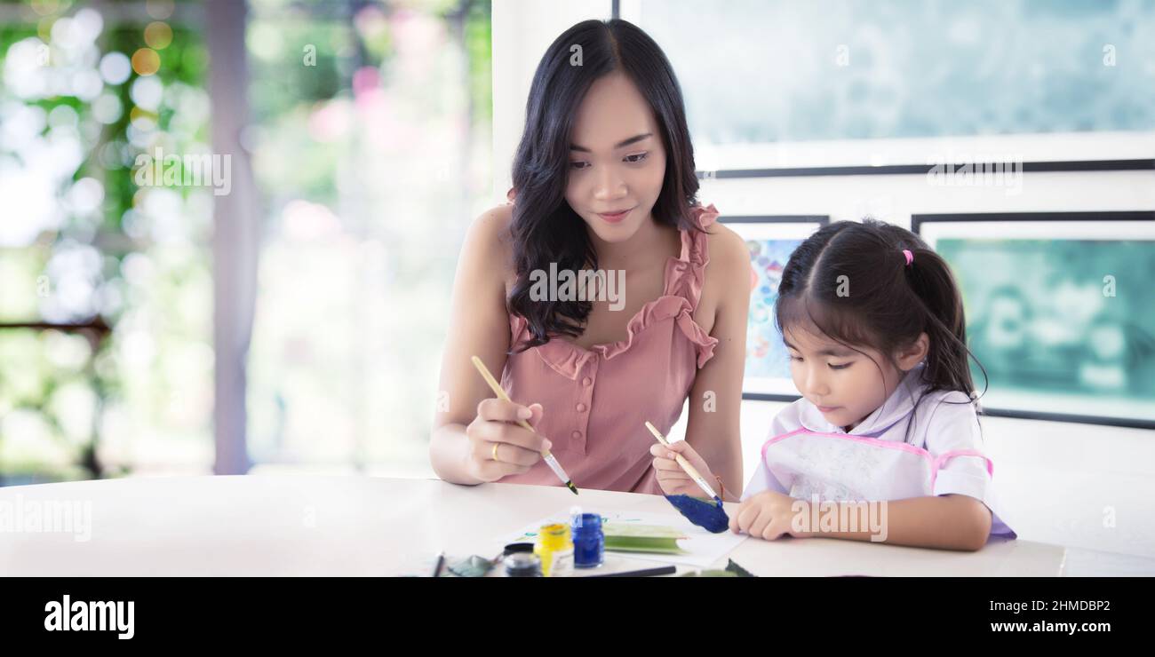 learning painting with mother and child at home. Asian family studying to learn art to develope imagination and skill at home. Education with love con Stock Photo