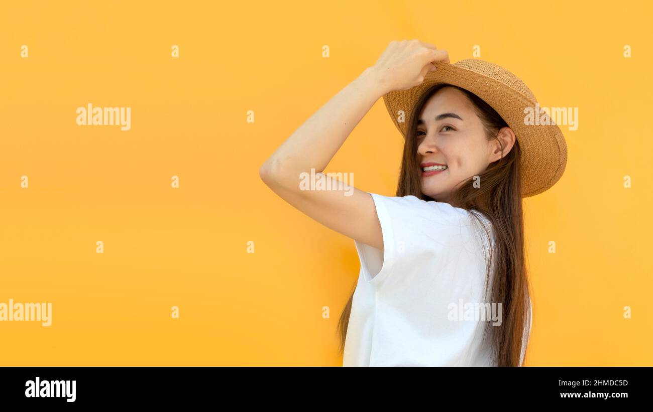 Portrait asian Woman against yellow Background .Asian woman wearing rattan hat , white shirt as traveller for advertising banner Stock Photo