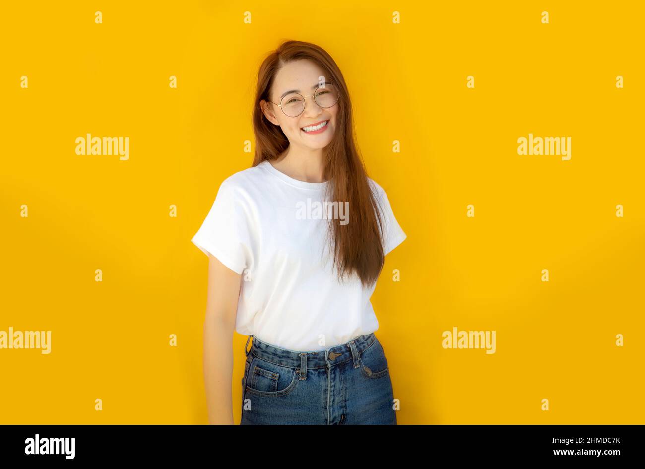 Portrait asian Woman against yellow Background.asian woman wearing glass, white shirt and blue jeans on yellow background for advertising banner Stock Photo