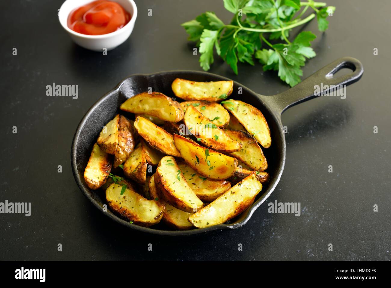 Roasted potato wedges with spices in frying pan Stock Photo