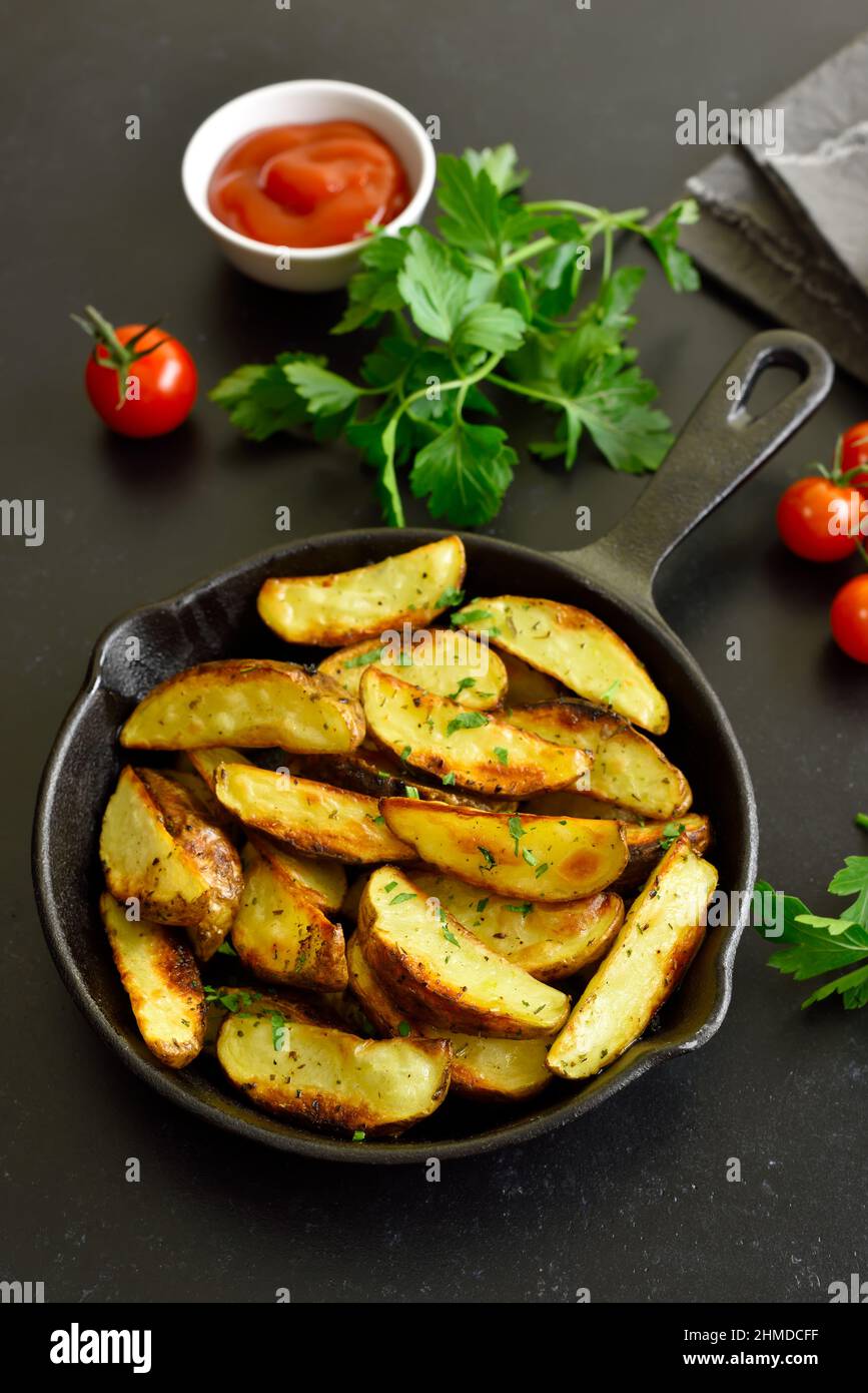 Roasted potato wedges with spices in frying pan Stock Photo