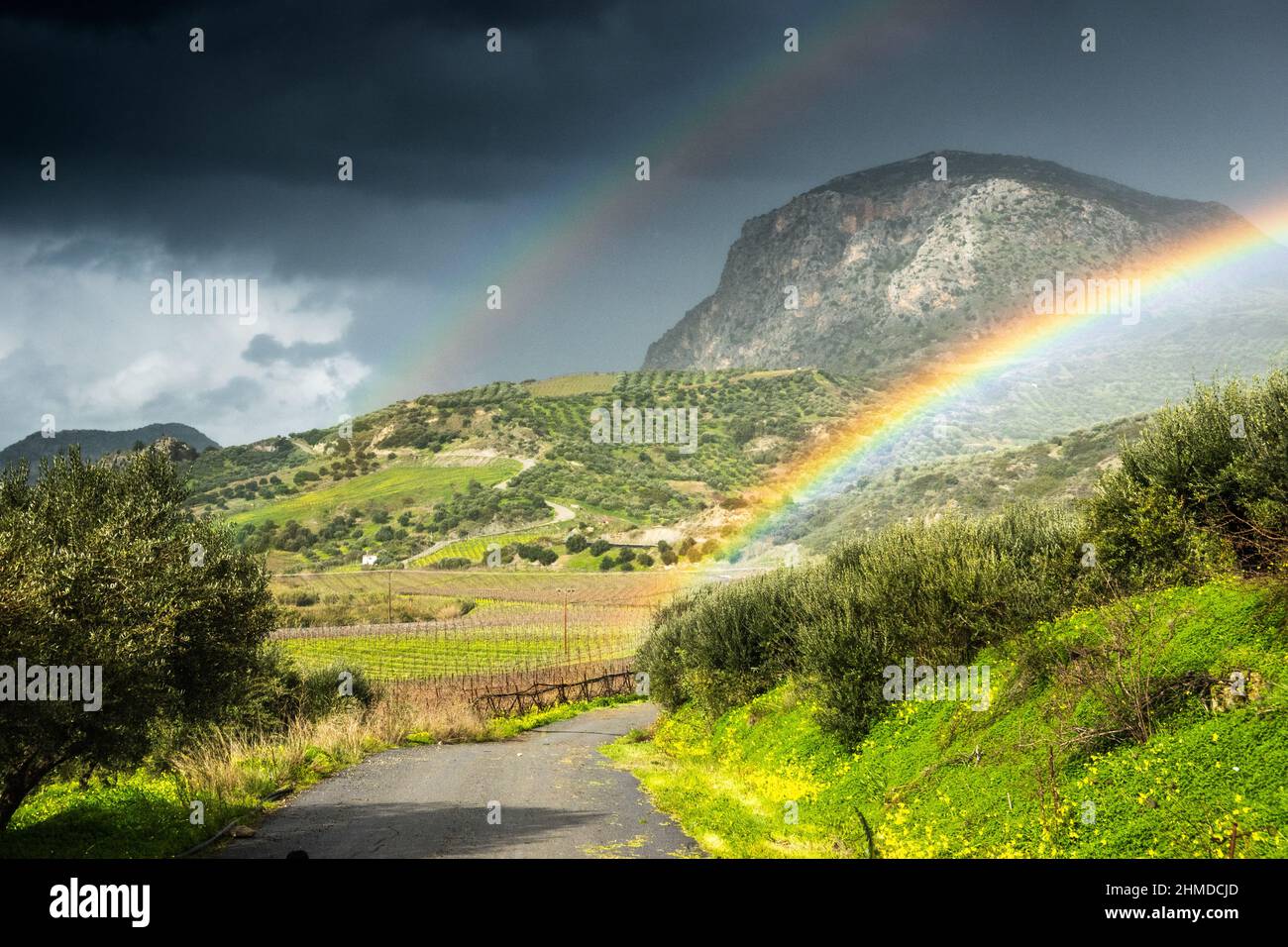 Beautiful double rainbow over green field against Storm cloud on sunny day Stock Photo