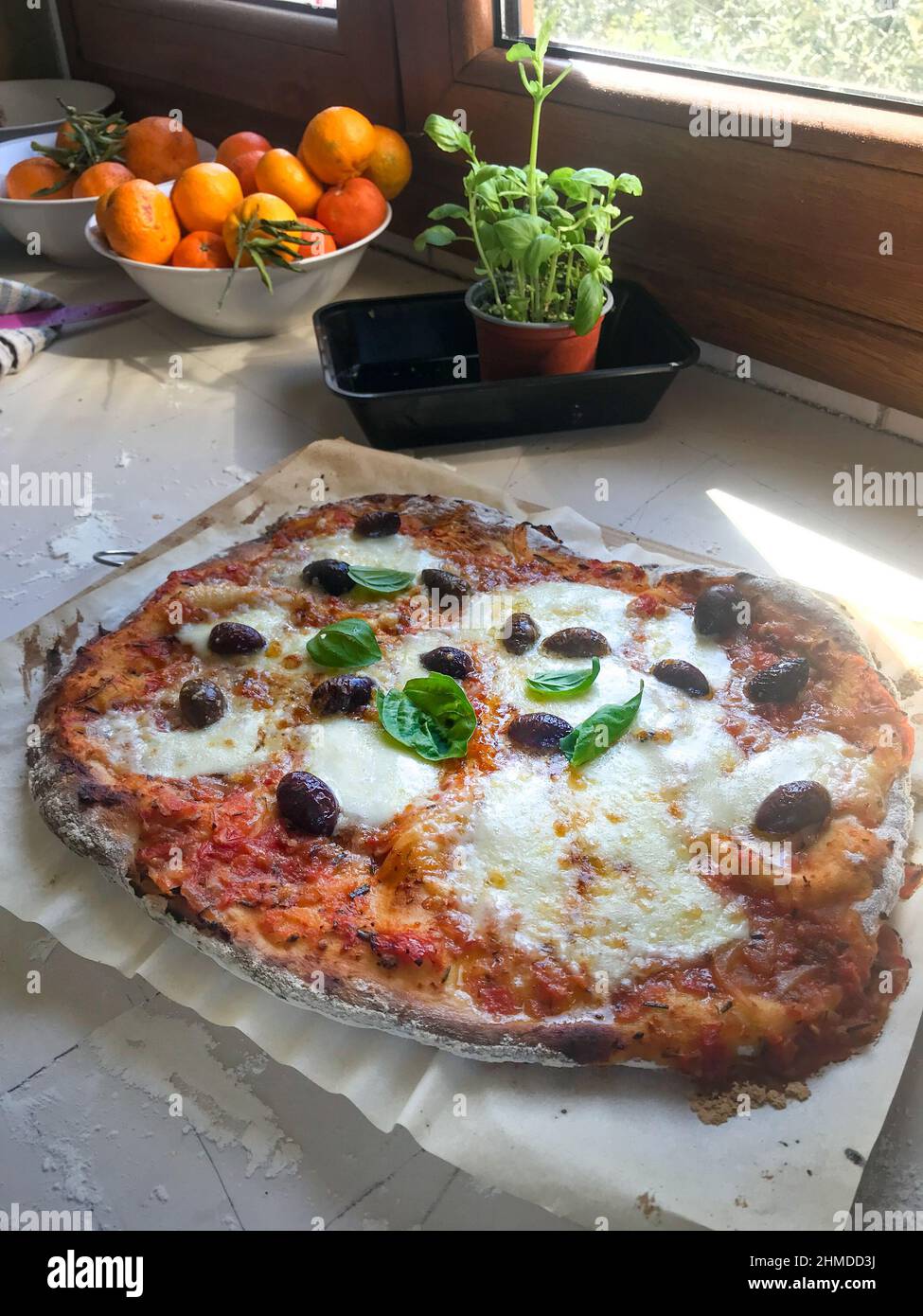 Freshly homemade pizza served in plate on window sill at home Stock Photo