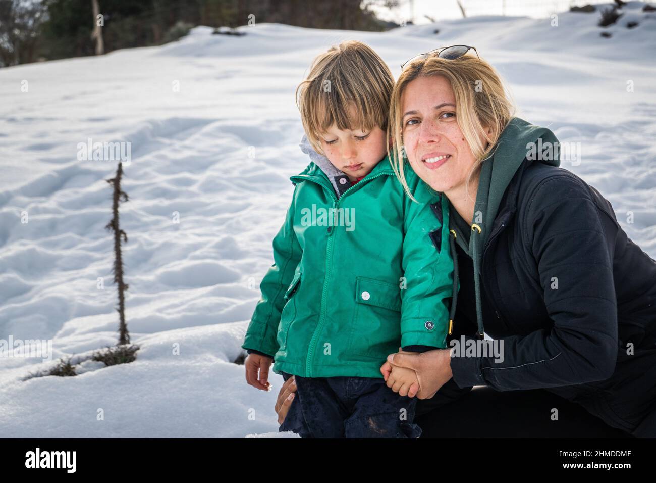 Happy mother holding little boy hand in snowy field Stock Photo