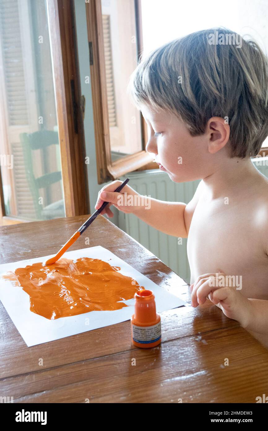 Little boy painting on paper using paintbrush at home Stock Photo