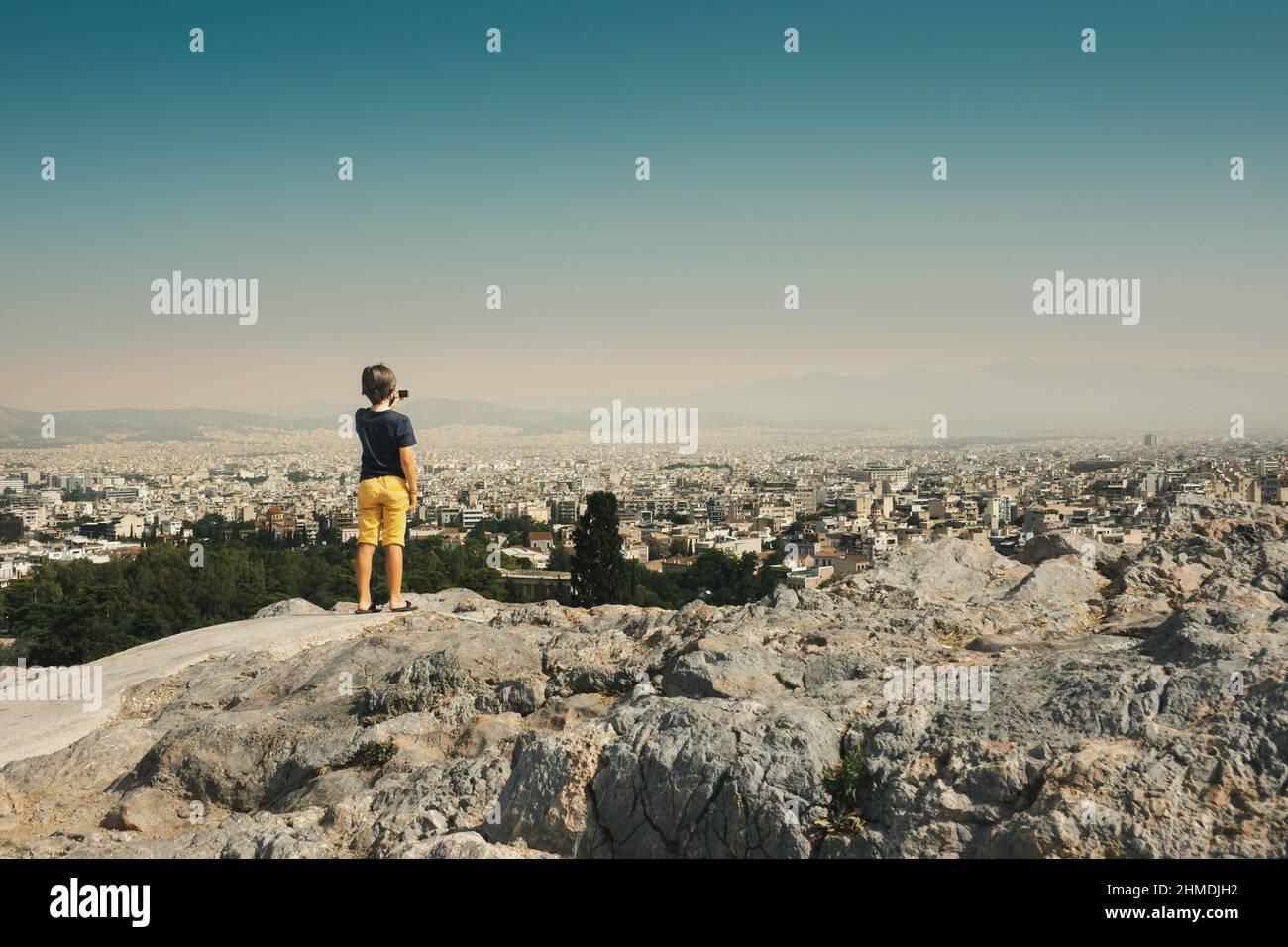 Rear view of boy photographing cityscape with camera, Athens, Greece Stock Photo