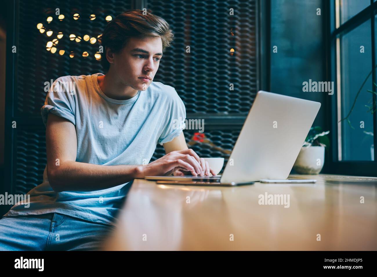 Focused freelancer using laptop for working in modern cafeteria Stock Photo