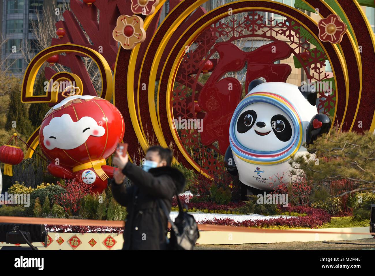 Beijing, China. 09th Feb, 2022. A tourist poses for a photo with the Winter Olympics mascot bing Dwen Dwen and the Winter Paralympics' Shuey Rhon Rhon in the background.The 24th Winter Olympic Games opened in Beijing, China. Beijing has become the only city in the world that has hosted both the summer Olympic Games and the Winter Olympic Games. (Photo by Sheldon Cooper/SOPA Images/Sipa USA) Credit: Sipa USA/Alamy Live News Stock Photo