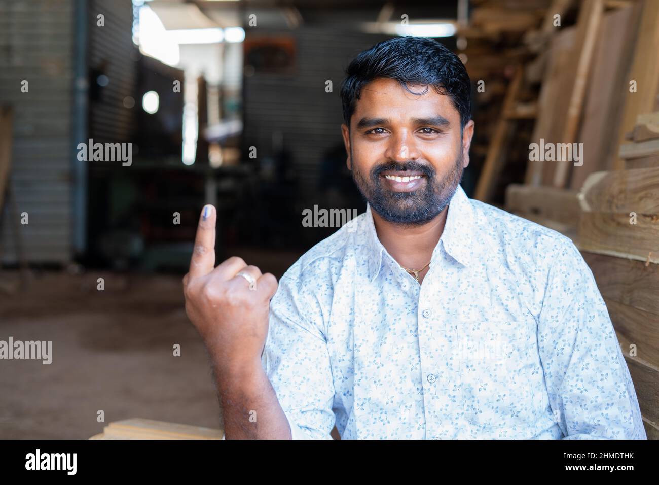 Happy indian carpainter or craftman showing ink marked finger by looking at camera after voting on election - concept of people voting rights Stock Photo