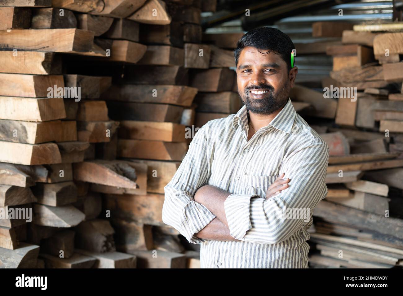 Confident smiling carpenter with arms crossed standing by looking at camera - concept of self confidence, skilled professional occupation and Stock Photo